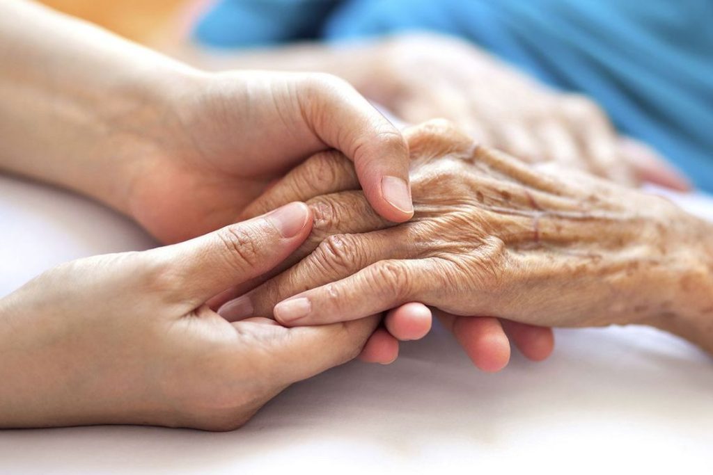 Main d'un proche tenant celle d'une personne âgée dans un moment paisible